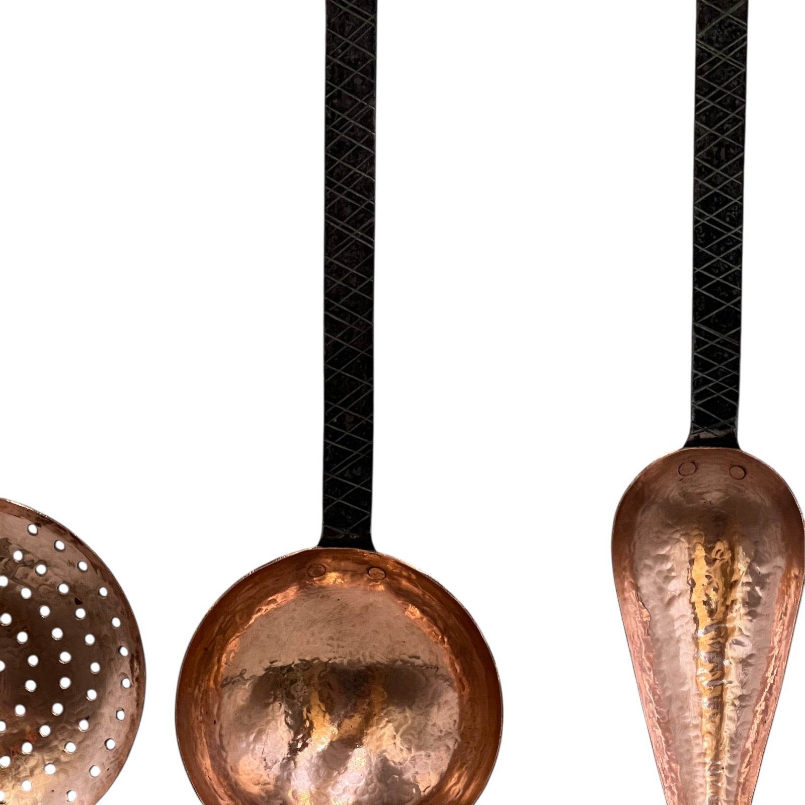 Close up of French copper kitchen utensils with black handles on a white background