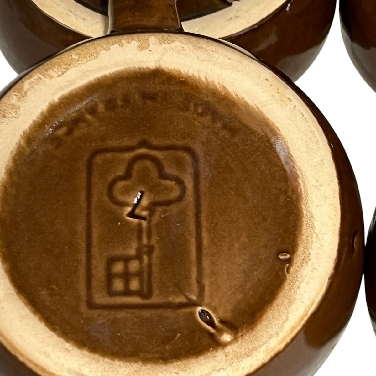 Close up detail view of Emile henry makers stamp in the shape of a key shown on a snail dish on a white background 
