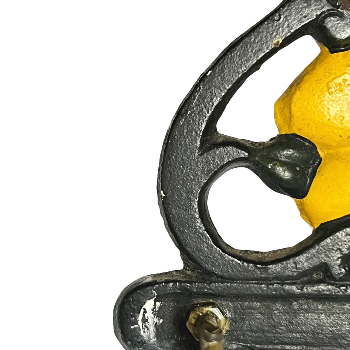 Close-up of a vintage cast iron wall hook with a yellow painted accent on a white background.