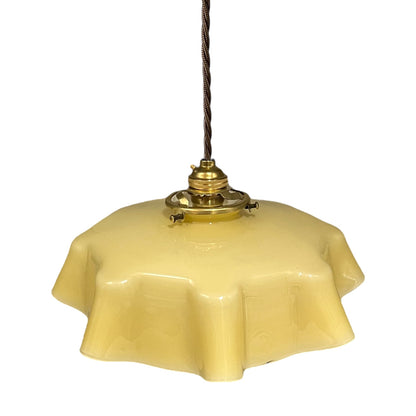 Vintage-style pendant light with a yellow glass shade and brass fitting on a white background