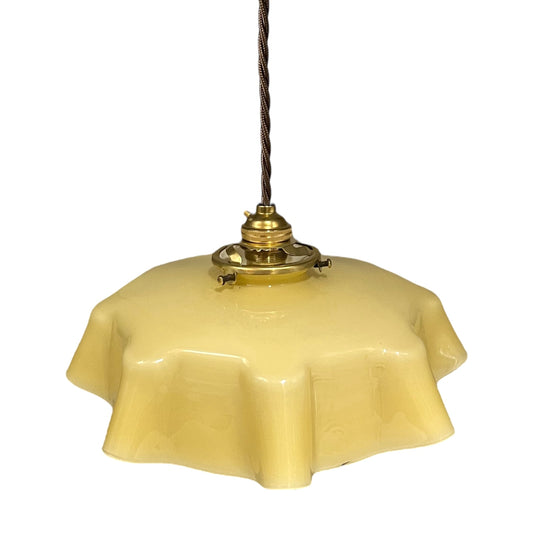 Vintage-style pendant light with a yellow glass shade and brass fitting on a white background