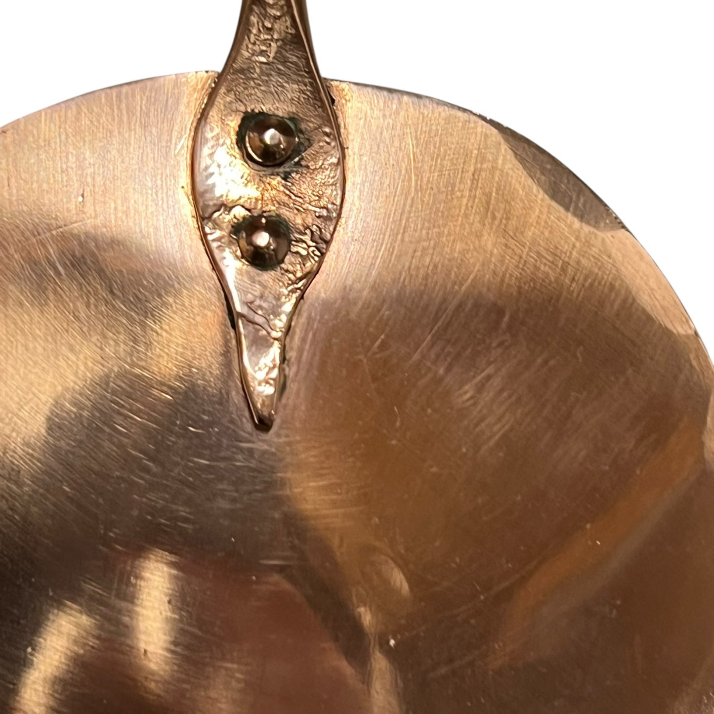 Close up of 3 copper utensils on a copper hanging bar on a white background