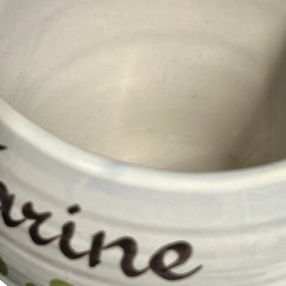 Close-up of the inside of a white ceramic mug or cup, showing part of a dark brown script word on the side.