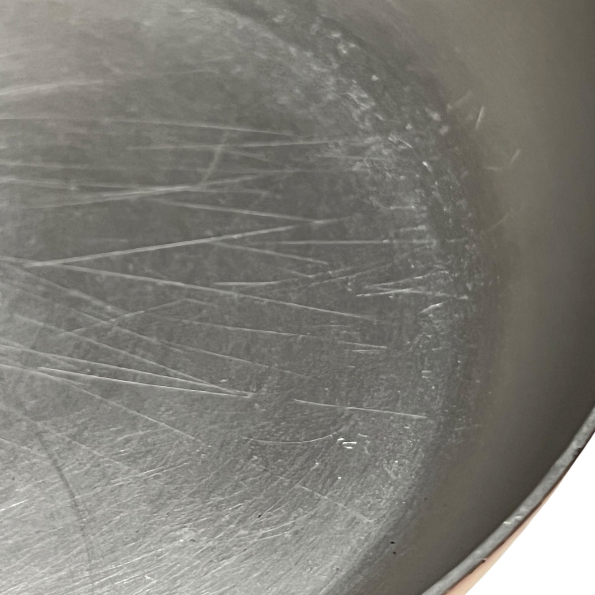 Close-up of the inside of a dark gray metal pot or pan showing visible scratches and wear on the brushed metal surface.