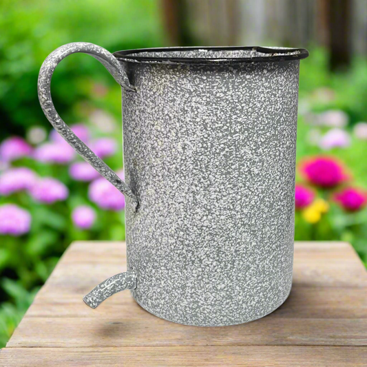 enamel grey speckled enamel planter  on a wooden surface with a garden background