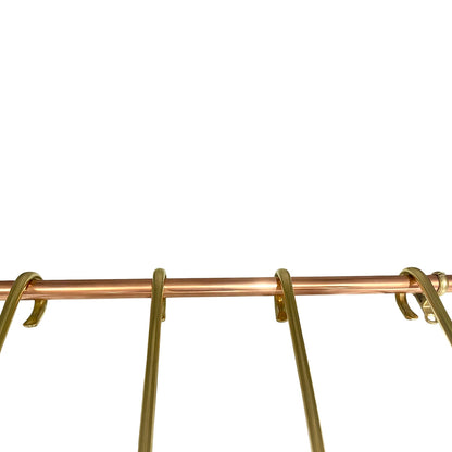 Close-up of a metallic gold and copper hanging rack bar with hooks against a solid white background.