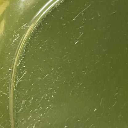Close-up of a green Le Creuset cast iron skillet on a white background 