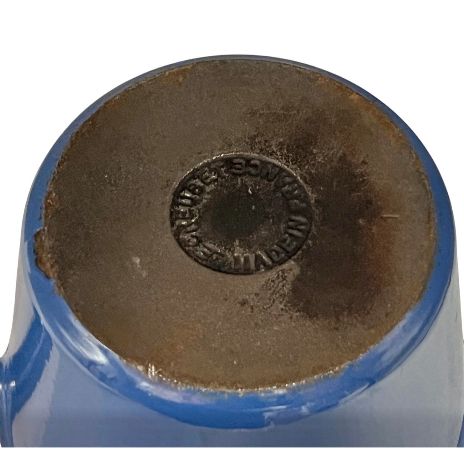 close up of blue cast iron pan with beige interior on a white background