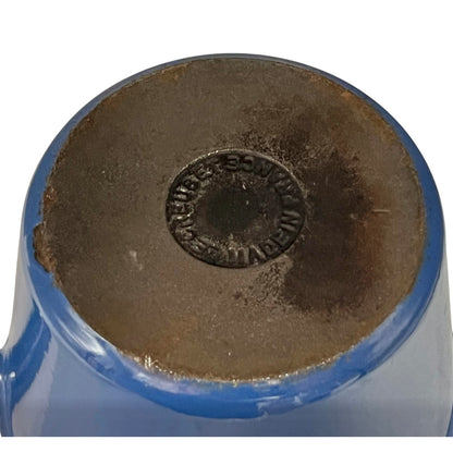 close up of blue cast iron pan with beige interior on a white background