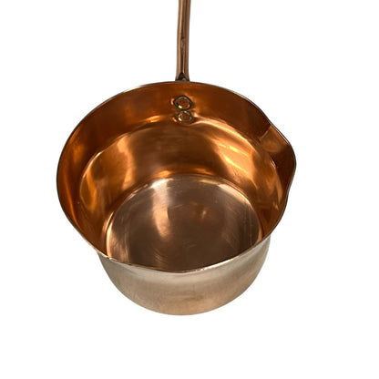 Close up of 3 copper utensils on a copper hanging bar on a white background