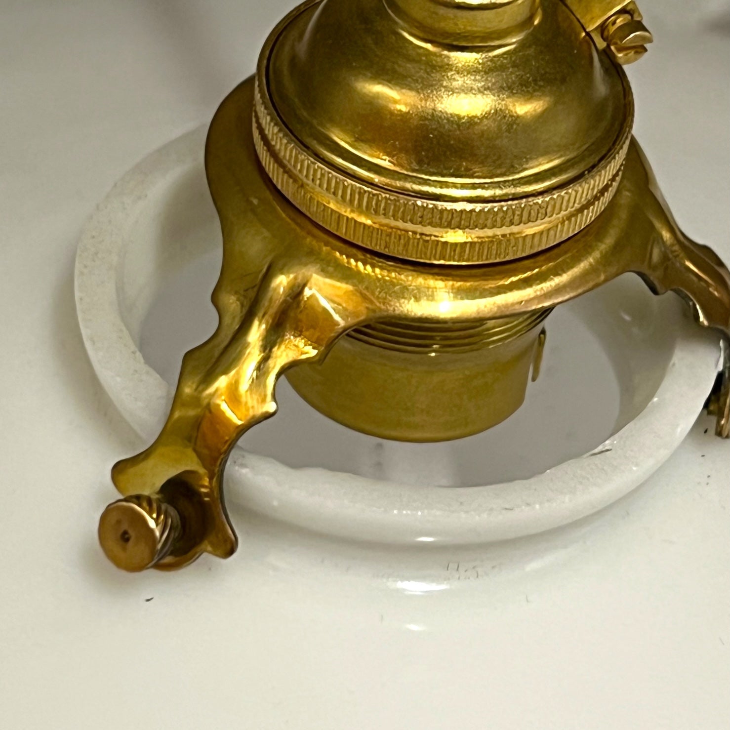 Close-up of a pendant light with white glass shade and brass fitting on a white background
