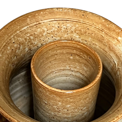 Close-up of a textured ceramic pot with a smaller cylindrical pot inside on a white background