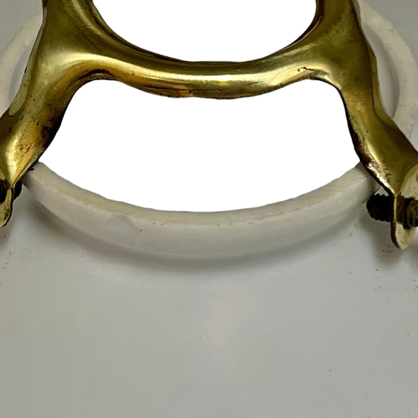 Close-up of a brass and white glass lampshade on a white background