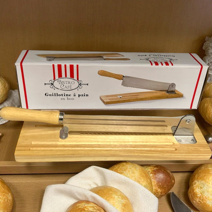 Wooden bread slicer with a box labeled 'Bistro Cafe' on a wooden surface with bread.