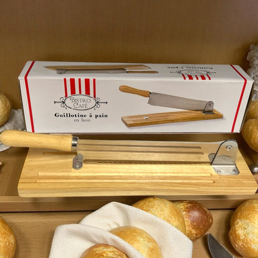 Wooden bread slicer with a box labeled 'Bistro Cafe' on a wooden surface with bread.