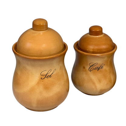 Two ceramic canisters with matching lids, one larger and one smaller, both in a warm tan and brown marbled glaze. The larger canister is labelled 'Sel' and the smaller canister is labelled 'Café' in black cursive script, set against a plain white background.