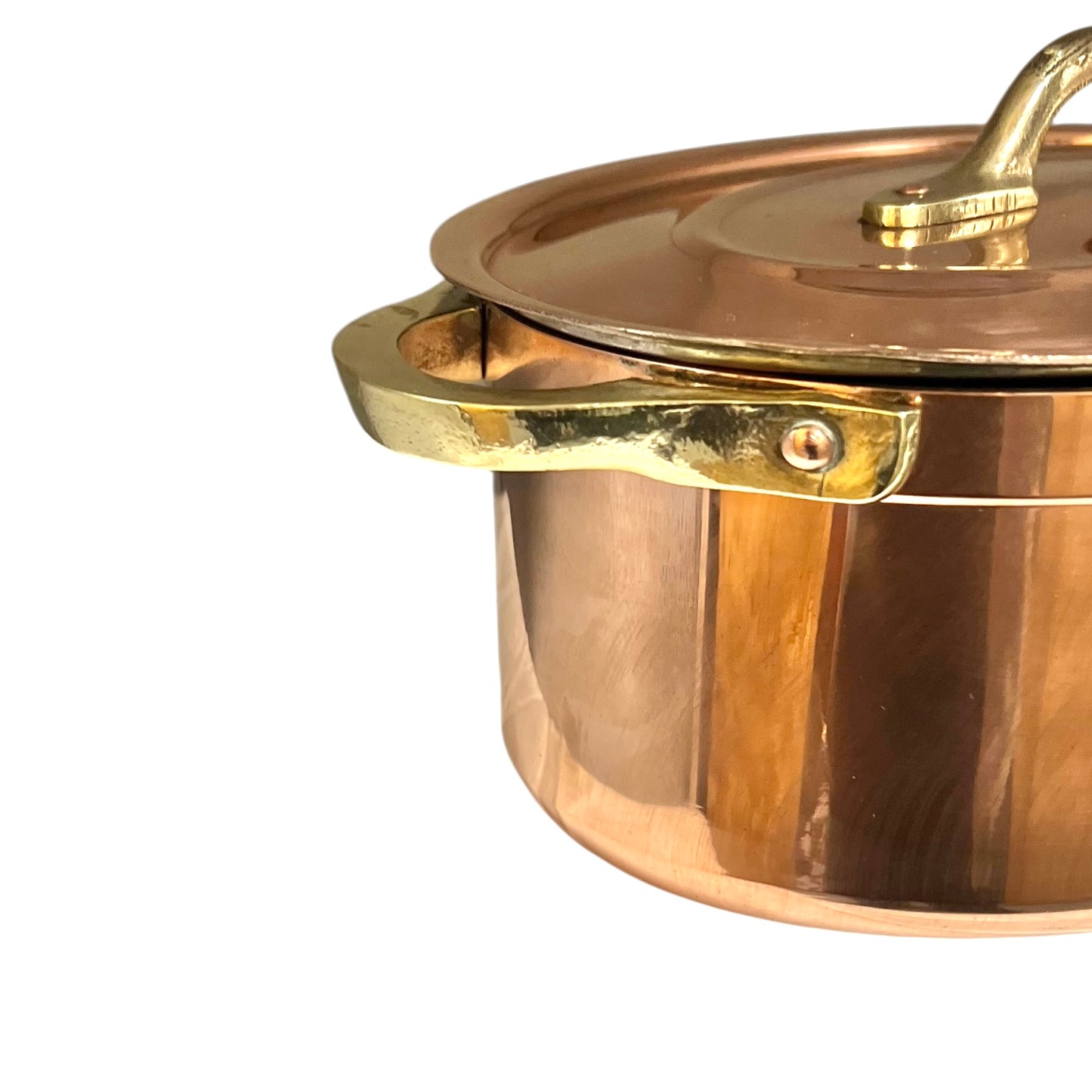 Close-up of a copper lid with a handle on a copper casserole pot