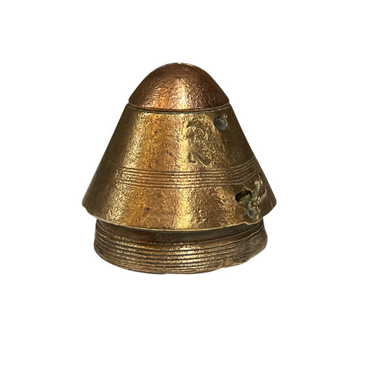 A small vintage brass ww1 paperweight with engraved lettering and ridged details, shown on a plain white background