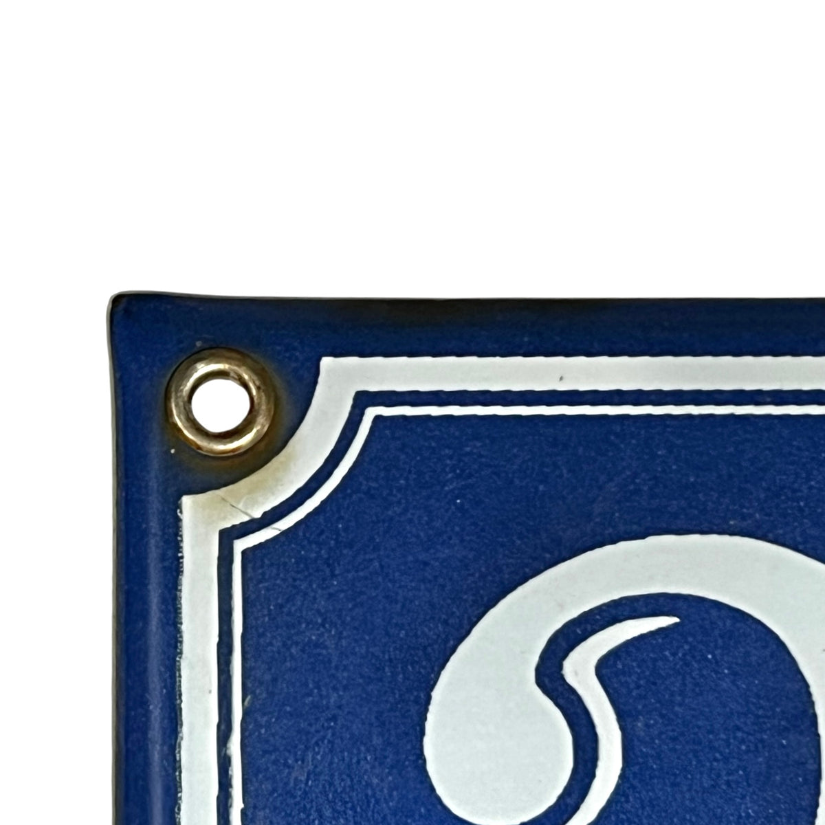Close-up of a blue decorative sign or plaque corner with a brass grommet and white border detail on a white background.