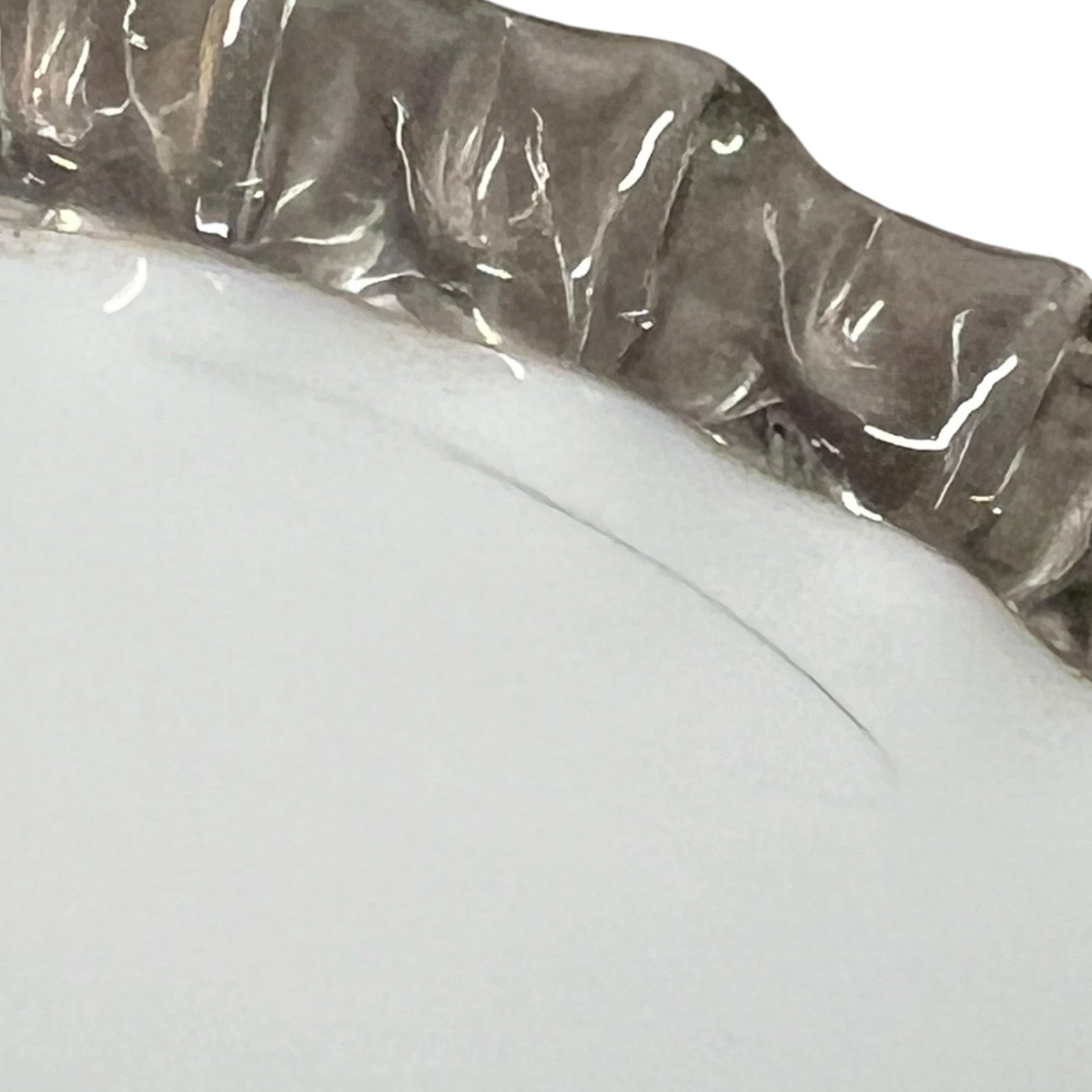 Close-up of a glass lampshade with a decorative edge on a white background