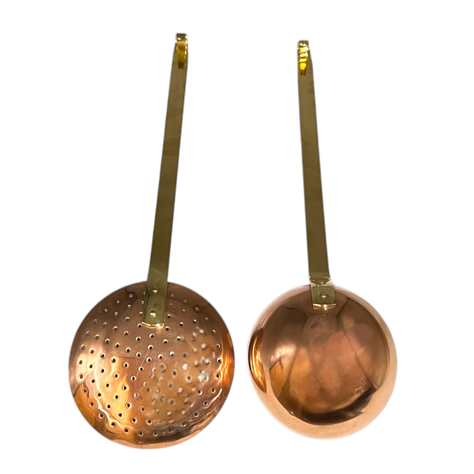 Set of 2 French copper utensils with long brass handles, includes a straining spoon and a ladle on a white background