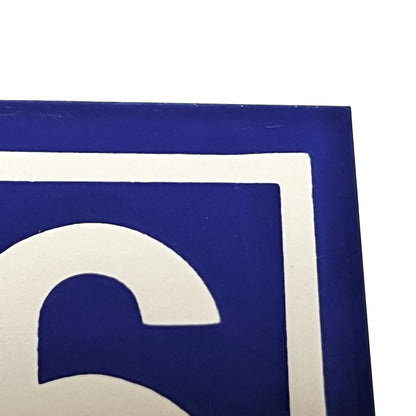 A close-up of a blue and white graphic design, showing a portion of a stylized white letter or symbol inside a blue square with a white border on a white background.