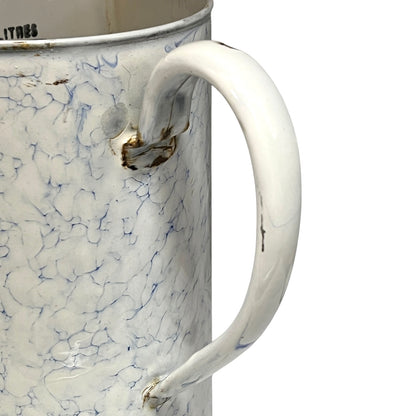 A close-up of a vintage enamel pot with a white handle and body, featuring a blue crackle pattern and distressed brown details near the rim and handle attachment.