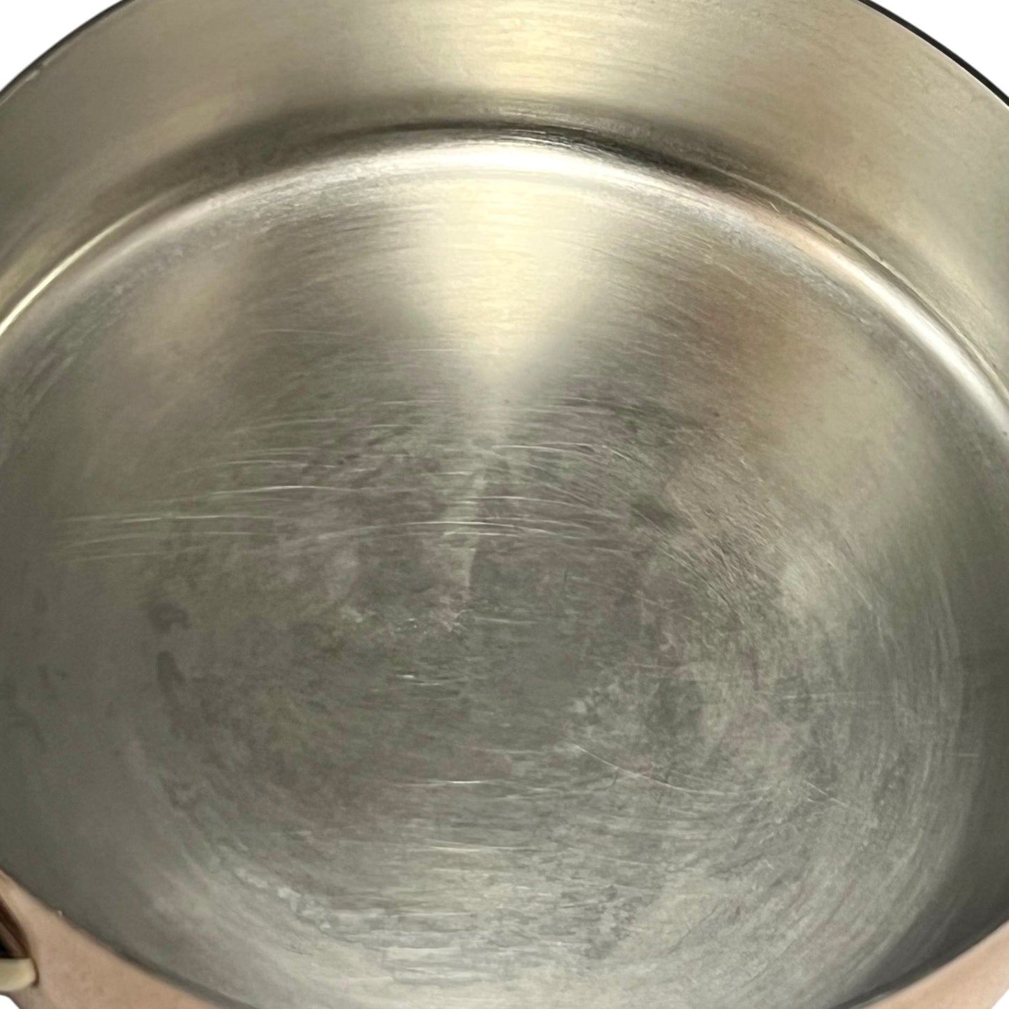 Small copper frying pan with a brass handle and tin lining on a white background