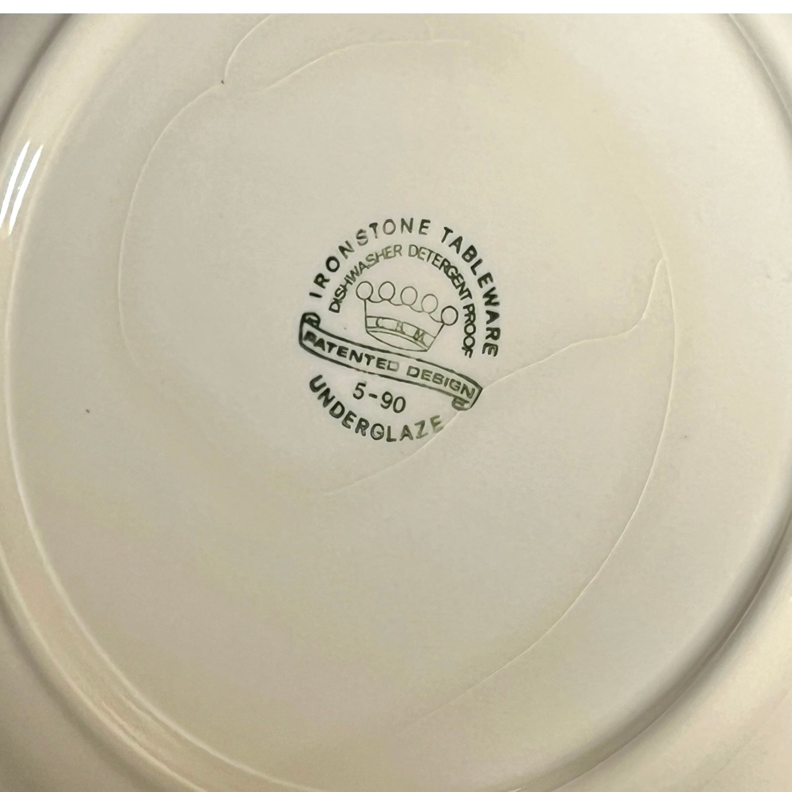 Close-up of a white ceramic plate with branding text on a white background
