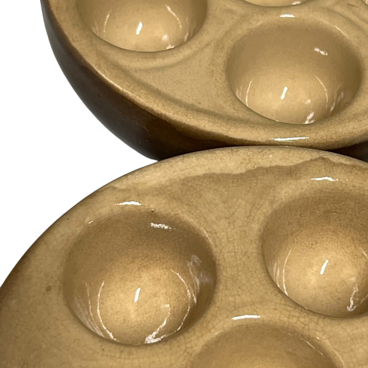 Close-up of a ceramic snail plate with multiple oval wells in a glossy light brown glaze, shown against a white background.