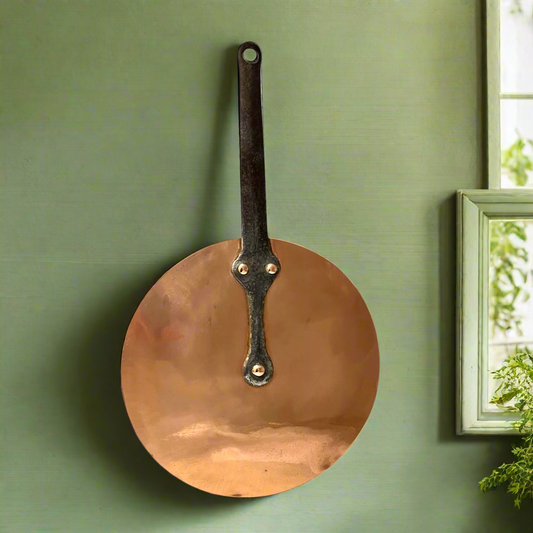 French vintage copper pan lid with new tin lining and a cast iron handle on a green background