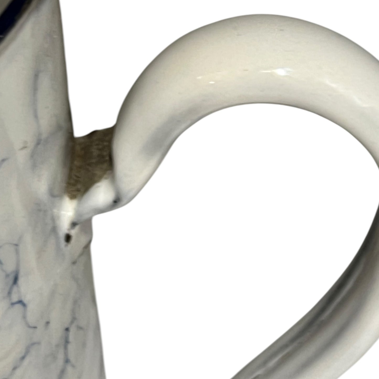 Close-up of a blue and  white pot handle and part of the marbled white body with subtle blue veining, isolated on a white background.