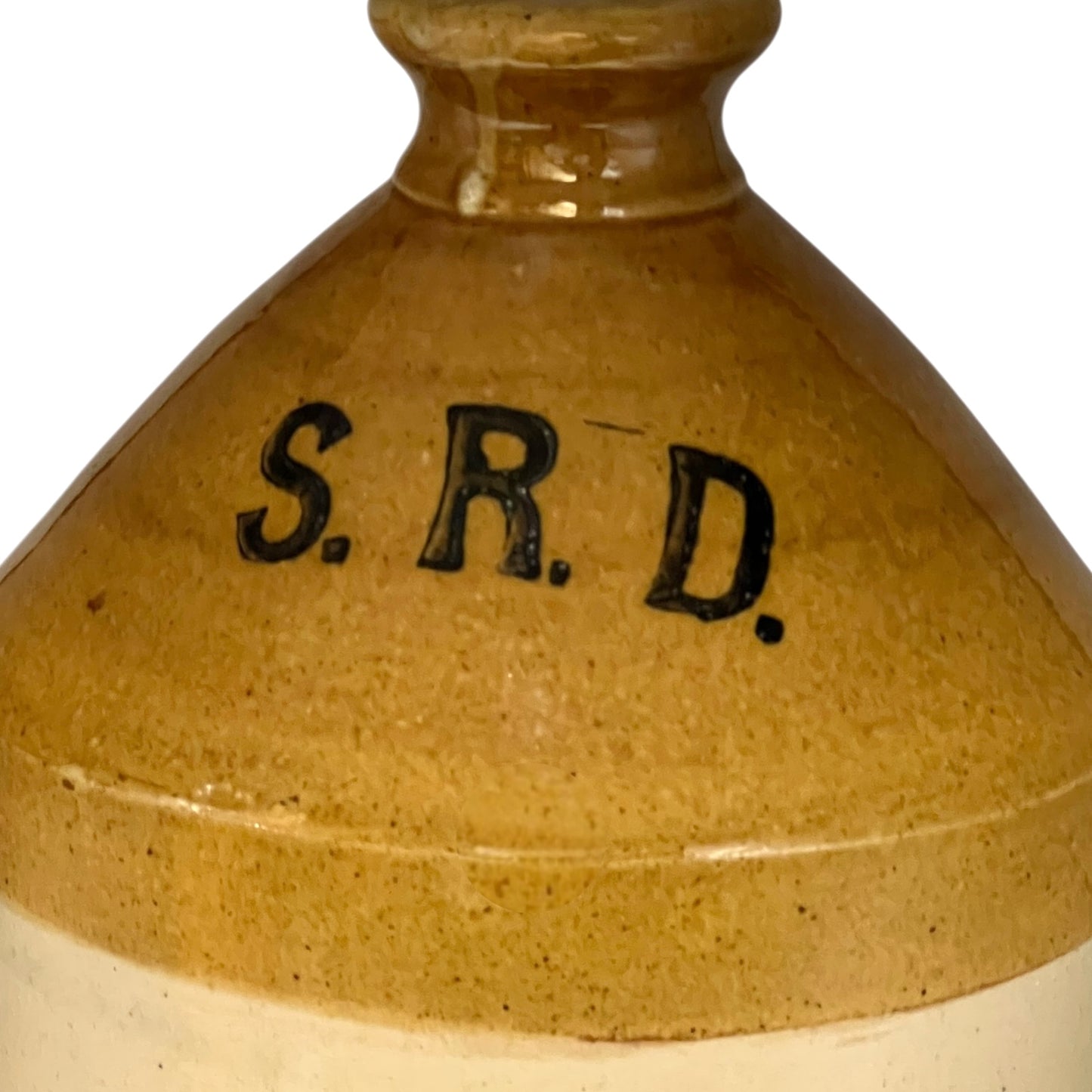 Close-up of a brown ceramic jar with 'S.R.D.' branding on a white background
