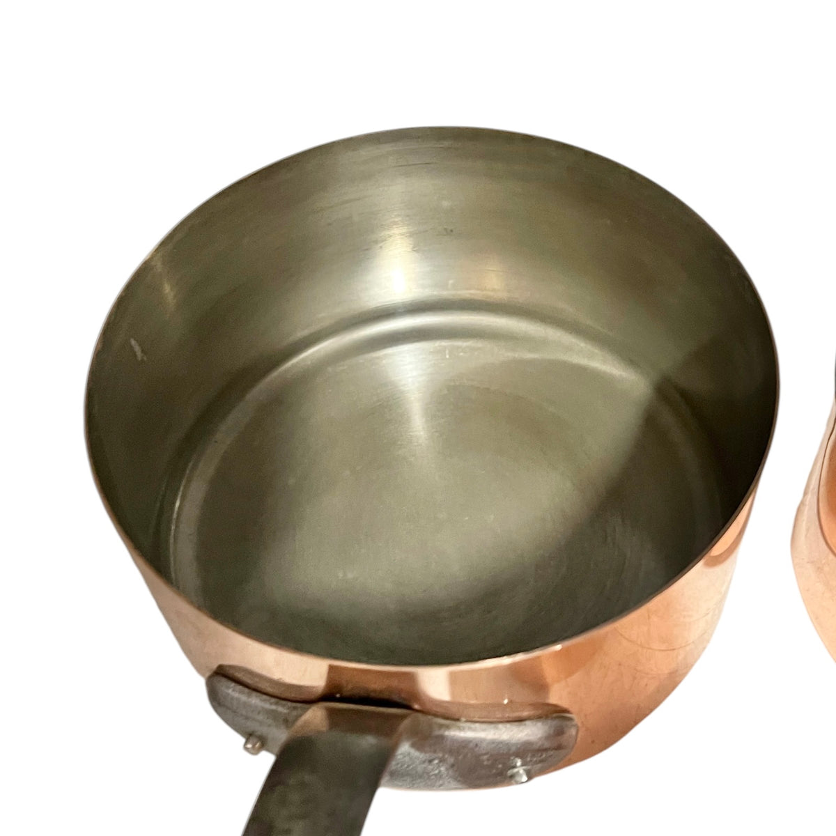 A copper saucepan with a brushed stainless steel interior and a copper exterior, shown from a top-down angle on a white background.