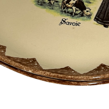 Ceramic plate with a scenic design and 'Savoie' text on a beige background