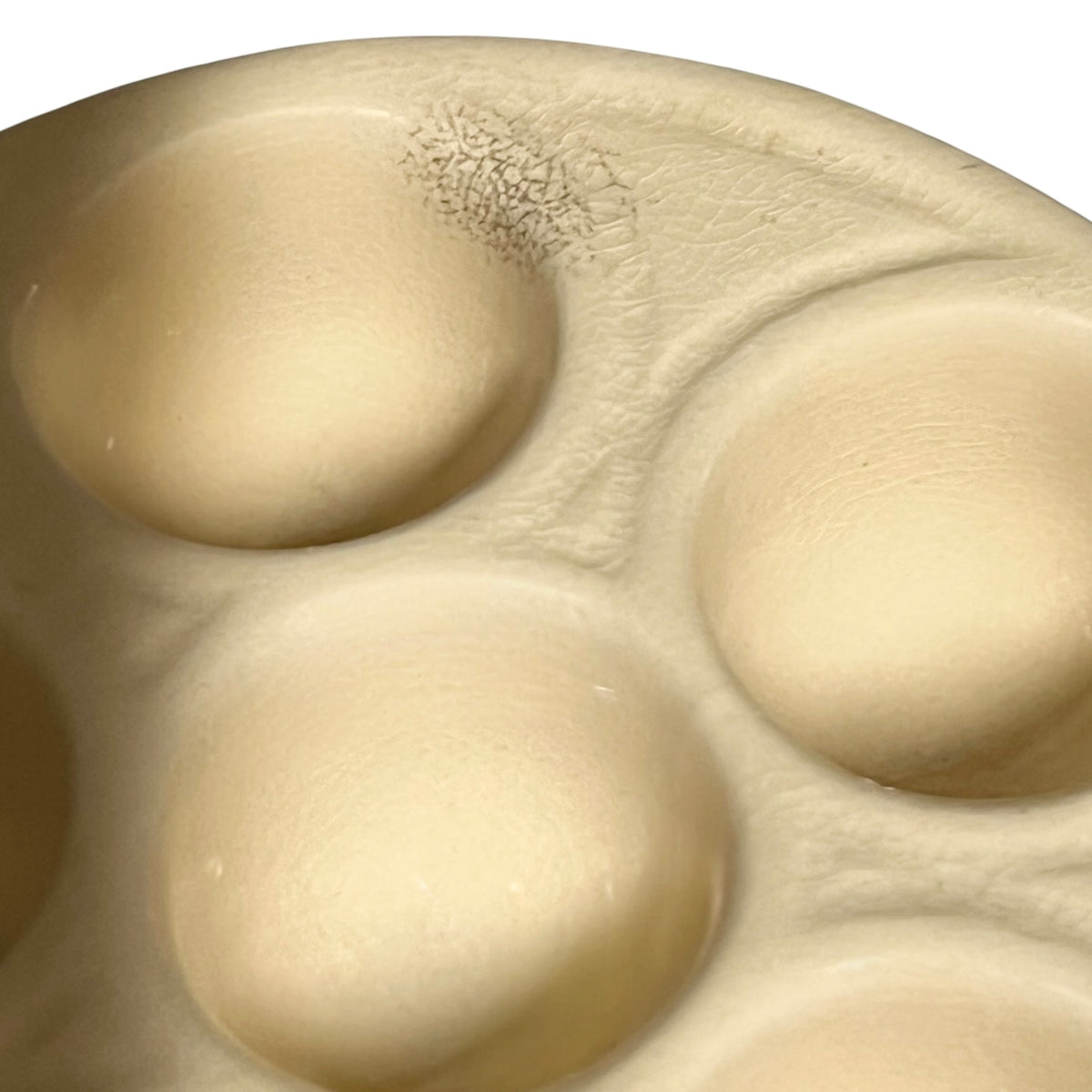 A close-up of a beige and brown escargot plate inner on a white background .