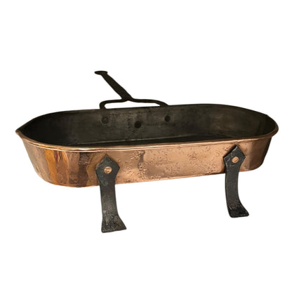 Antique French copper roasting pan with a long handle on a white background