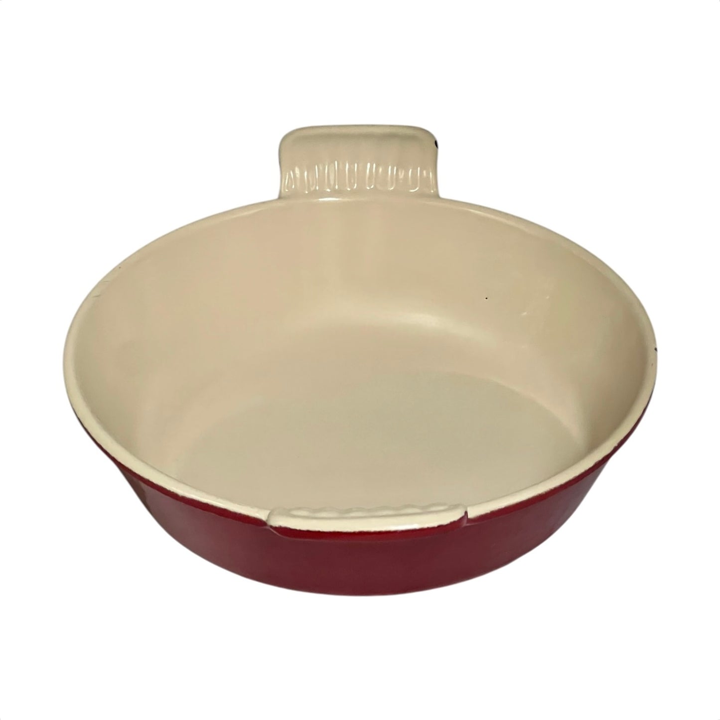 A round ceramic baking dish with a cream-colored interior and a dark red exterior, featuring a small handle on top.
