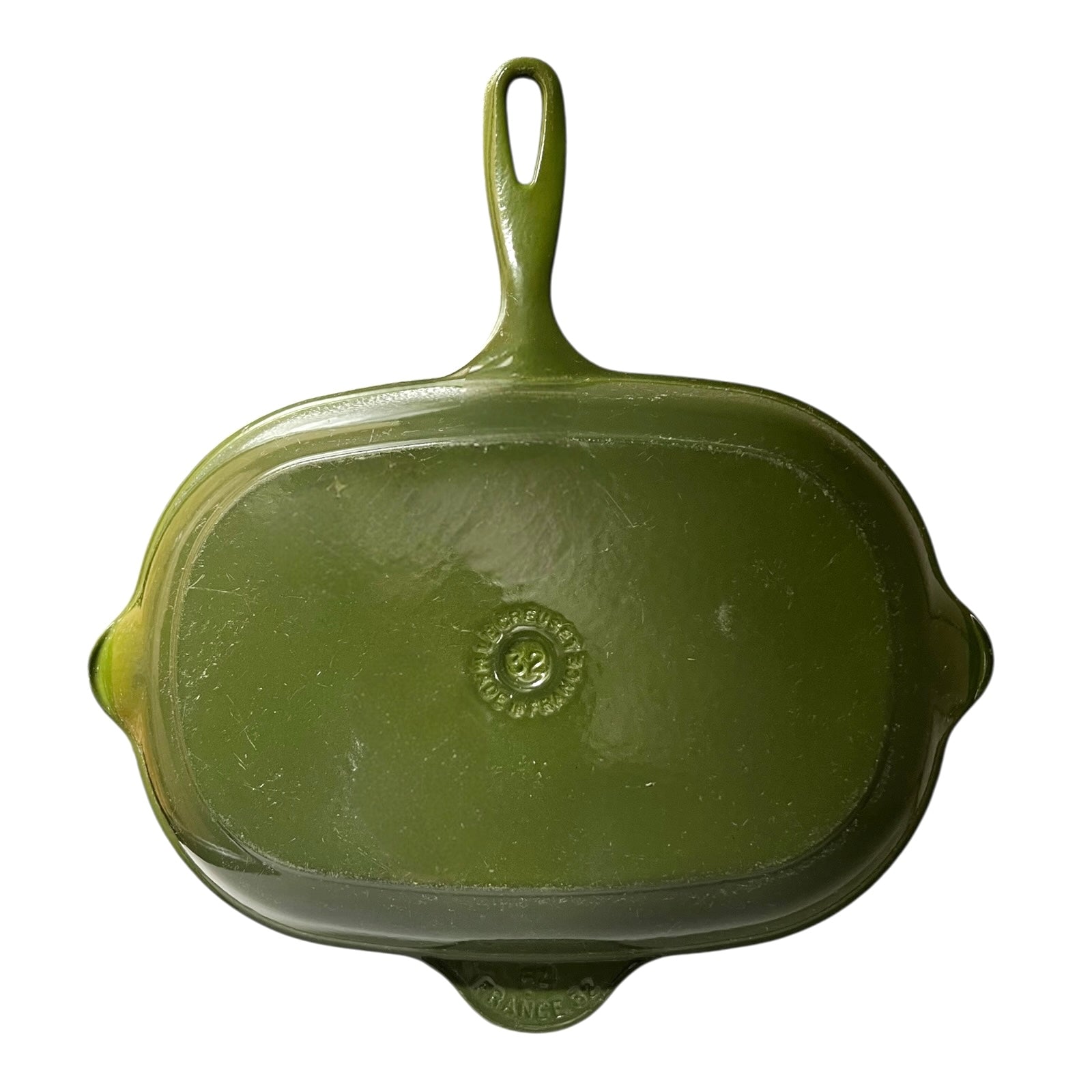 Green Le Creuset grill skillet pan with black cast iron inner on a white background