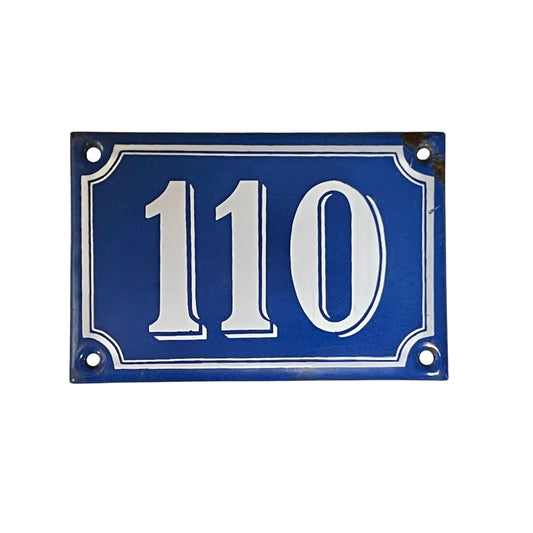 Blue house number plate with white text '110' on a white background