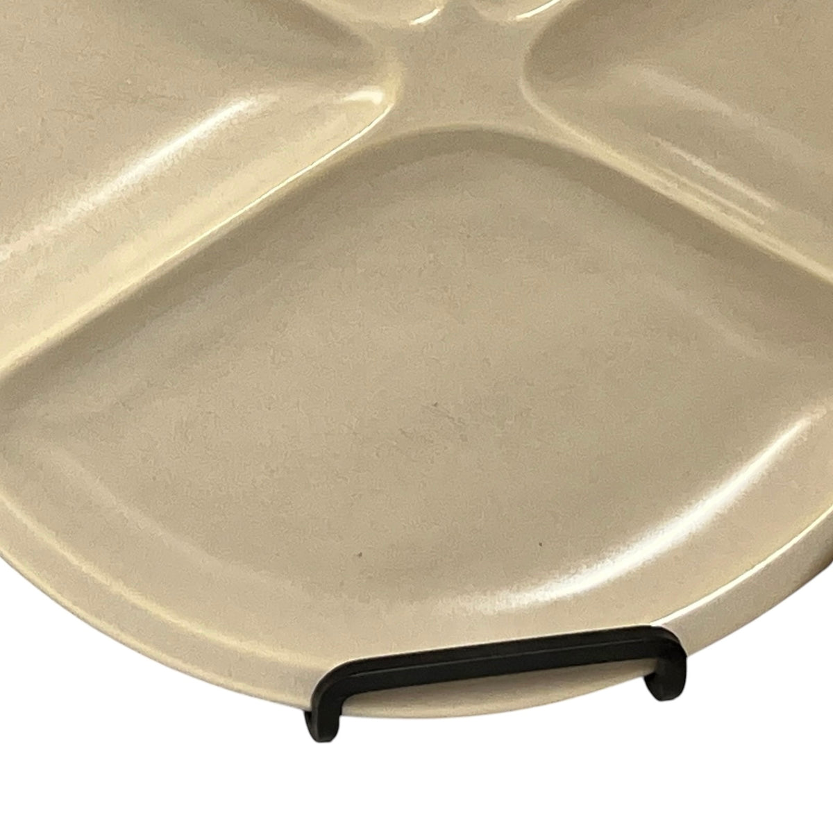 A close-up of a beige ceramic divided plate with a black plastic handle, shown against a white background.