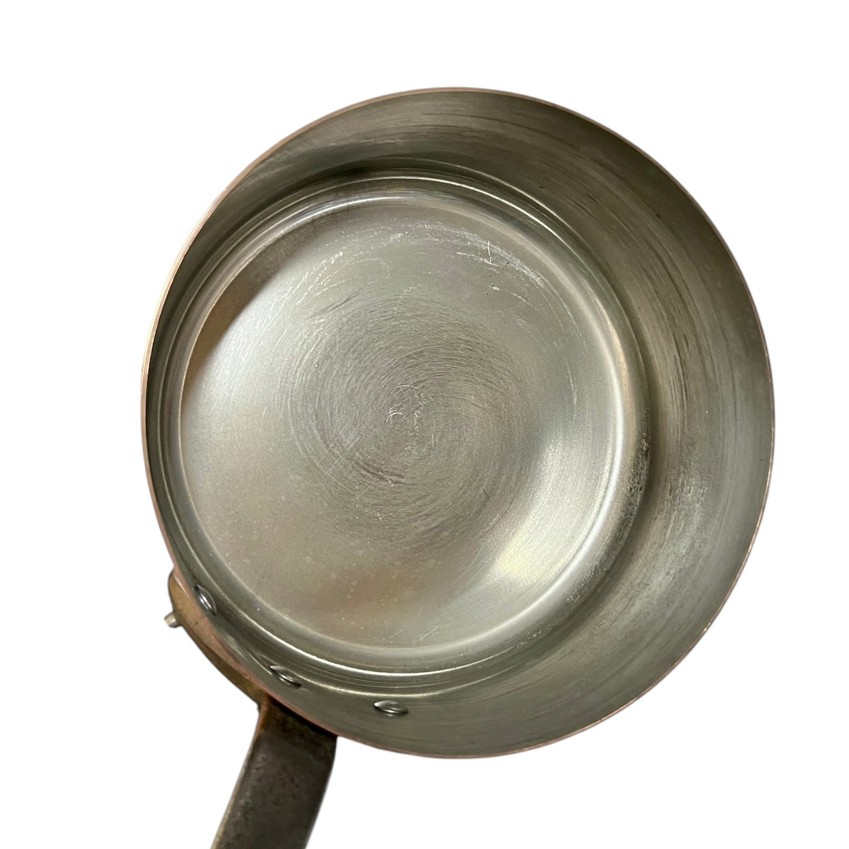 A top-down view of a tin lined copper saucepan with a brushed metal interior and a dark handle, isolated on a white background