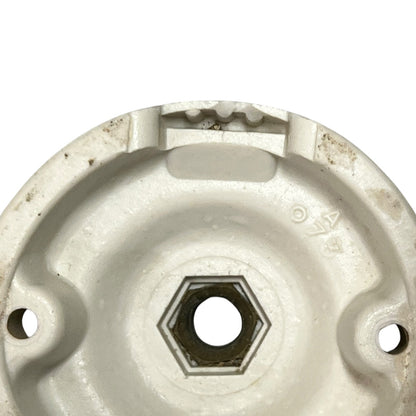 Small vintage French porcelain ceiling rose with a brass nut on a white background 