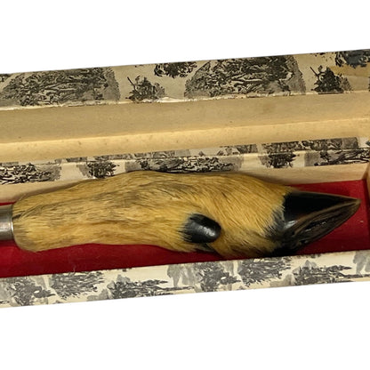 A decorative knife with a real deer hoof handle, featuring a tan and brown textured body, a black beak, and a black eye, resting inside its patterned presentation box