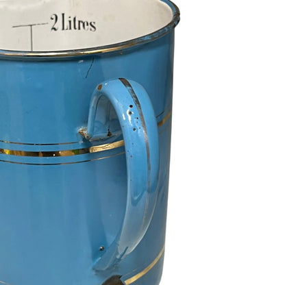 A close-up of a vintage blue enamel planter with gold stripes, a white interior, and a handle, showing the text '2 Litres' printed inside.