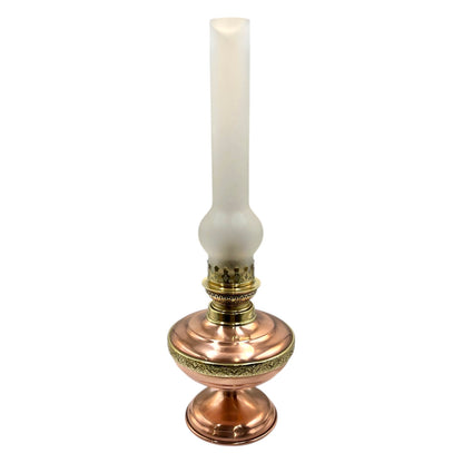 Decorative copper and brass oil lamp with a frosted chimney on a white background