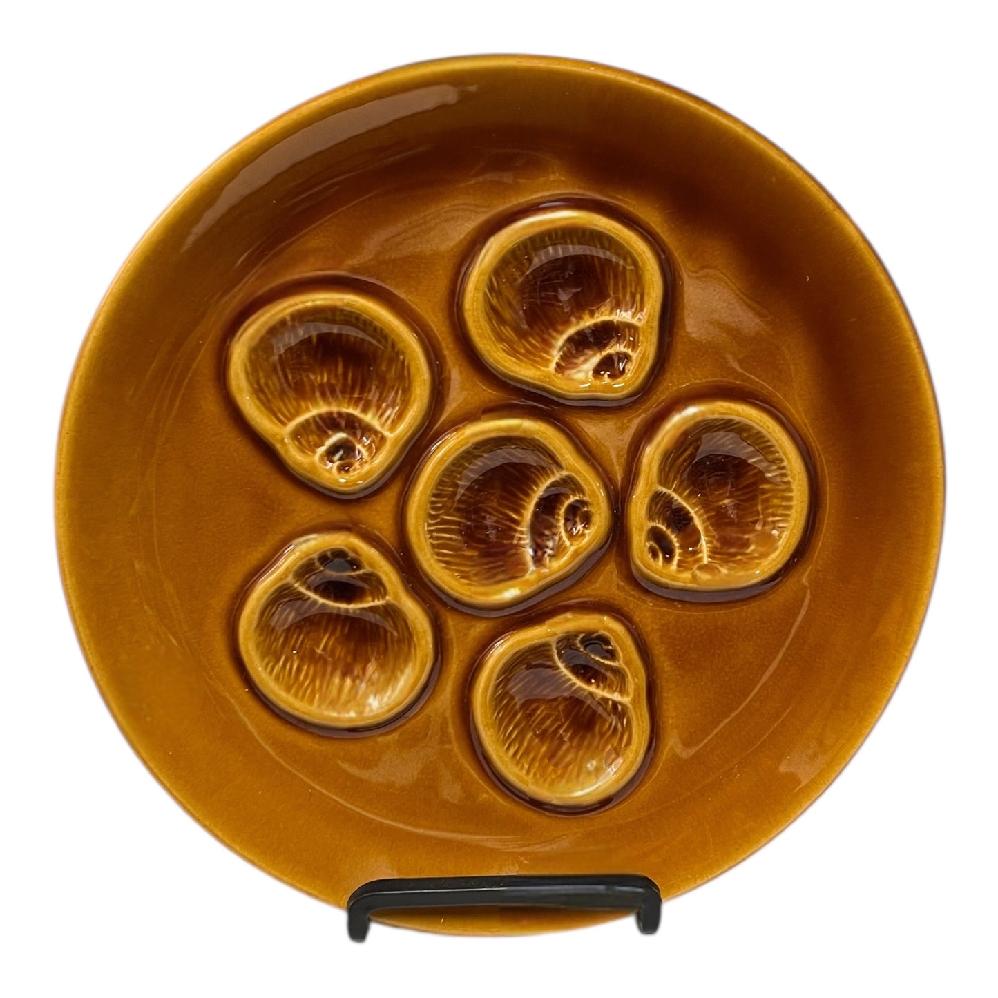 Brown ceramic plate with six circular depressions on a white background