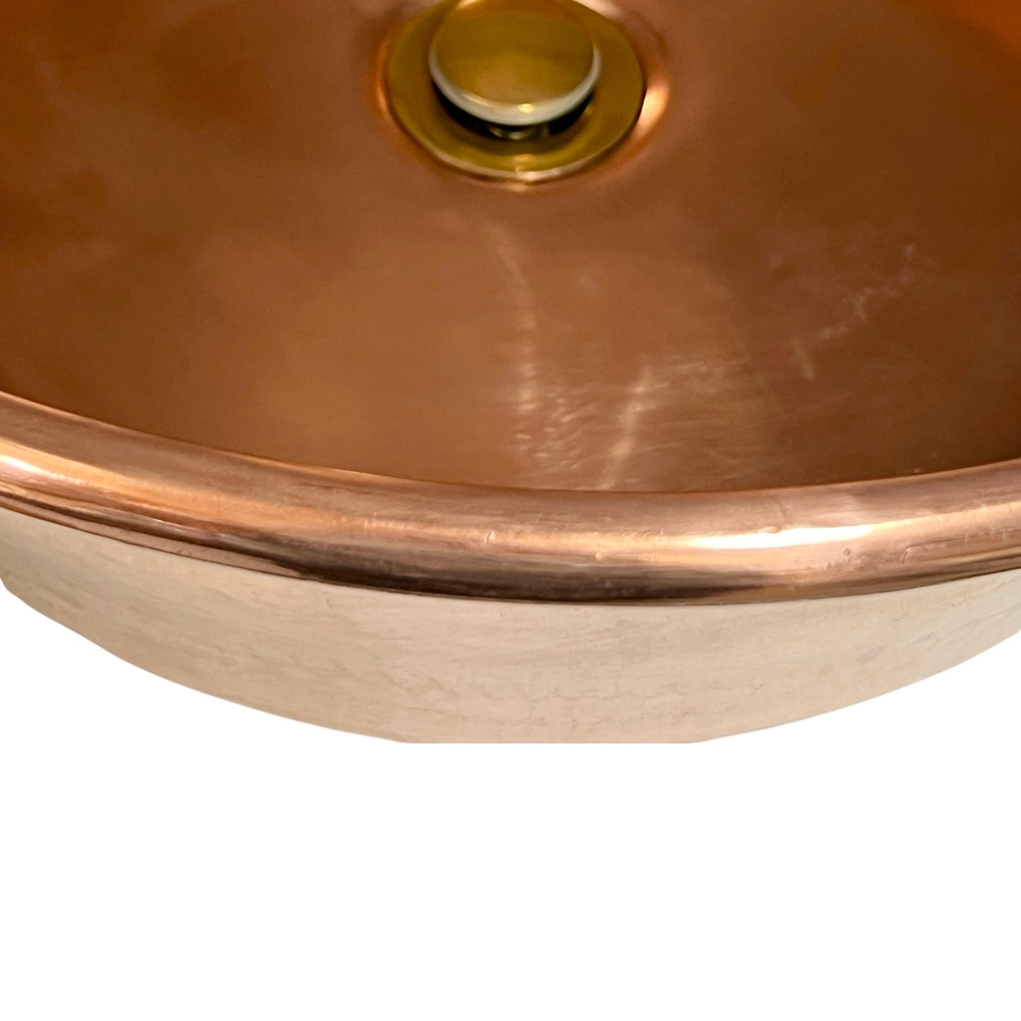 Close-up of copper sink with brass pop up waste on a white background