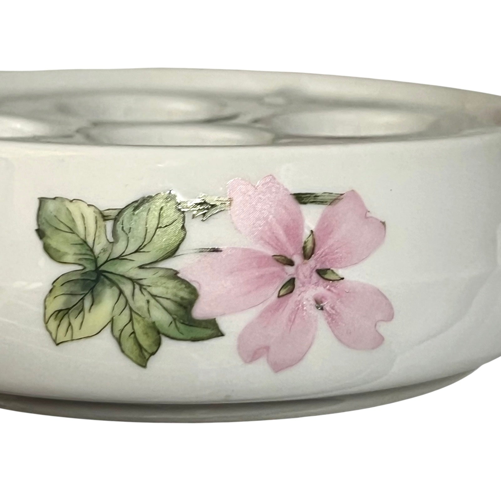 A white ceramic bowl featuring a hand-painted pink flower and green leaves on the side, shown against a plain white background.