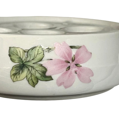 A white ceramic bowl featuring a hand-painted pink flower and green leaves on the side, shown against a plain white background.